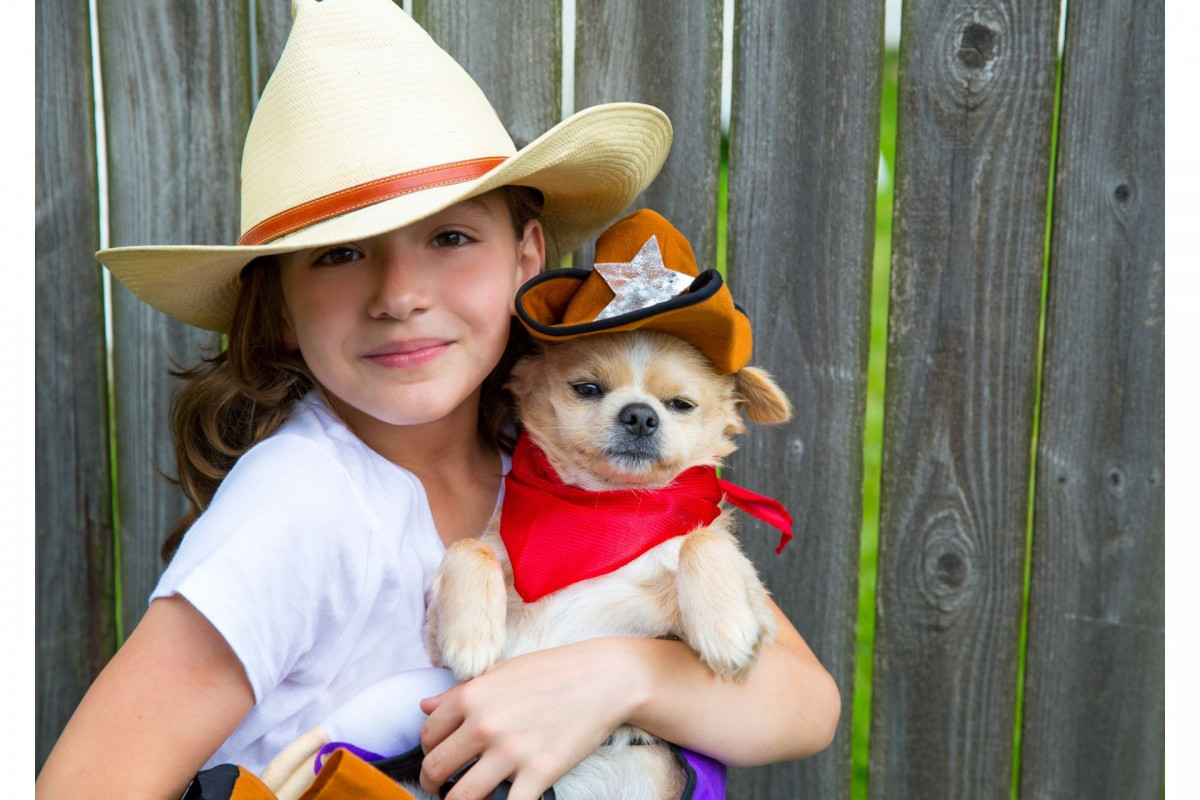 Girl holding a small dog, both wearing cowboy hats