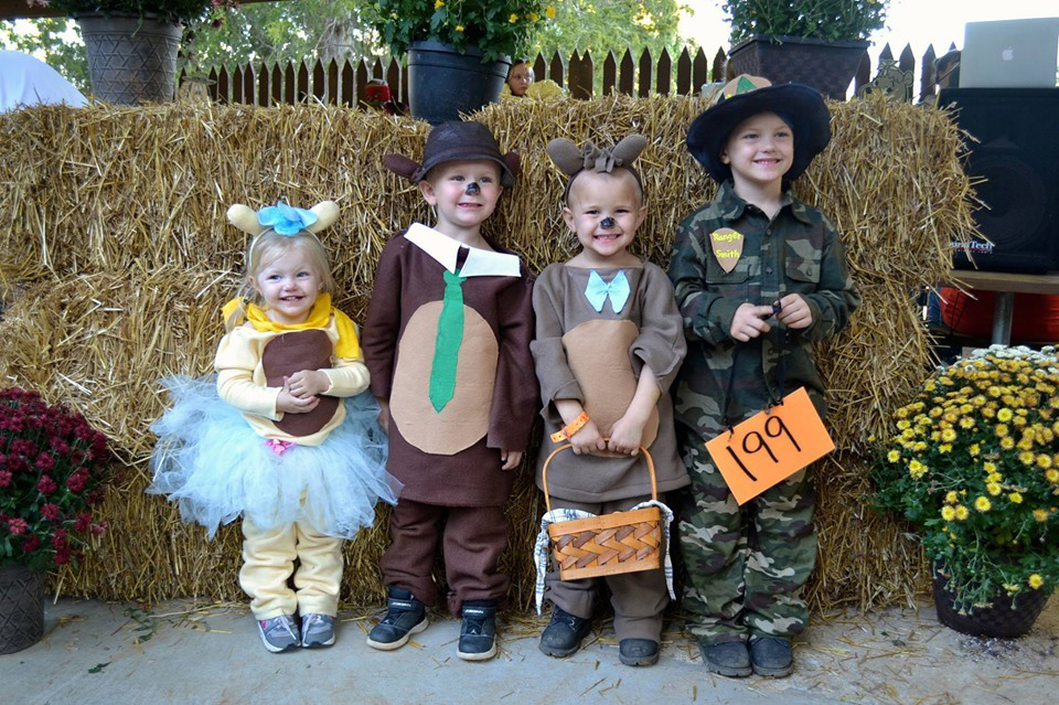 Children in Halloween costumes by bales of hay