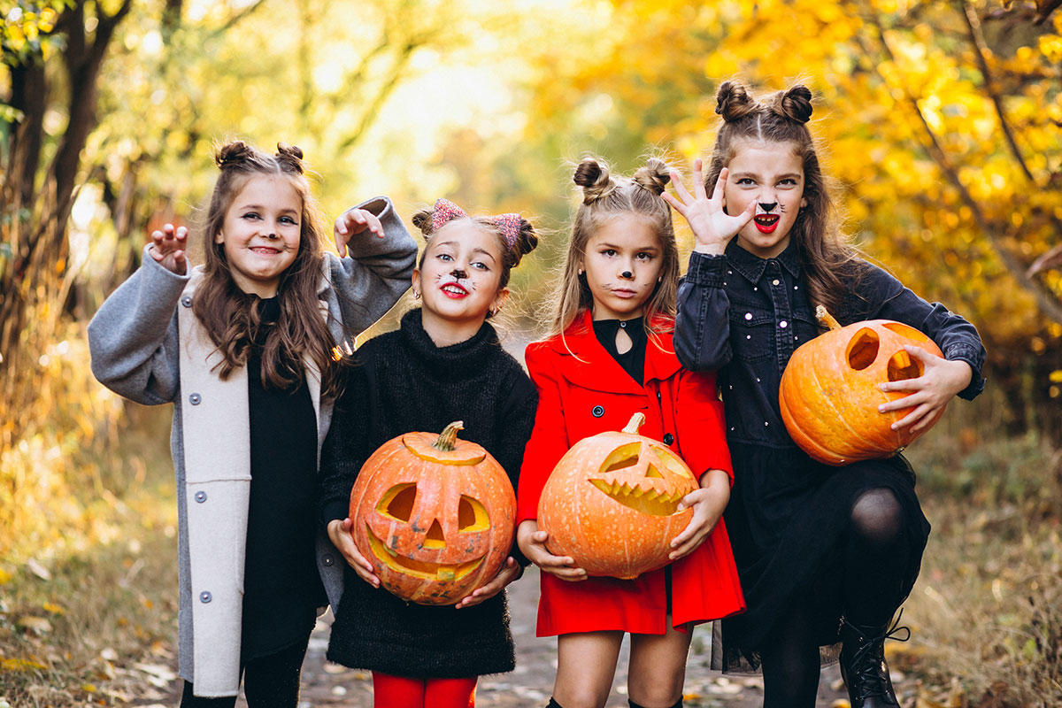 Children in halloween costumes holding pumpkins