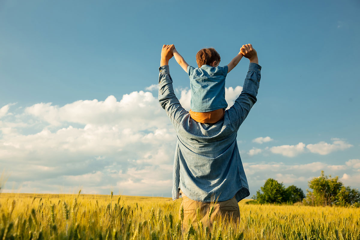 Dad with son on his shoulders in a field