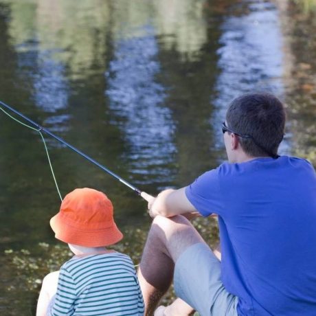 Man and child fishing together in a large body of water